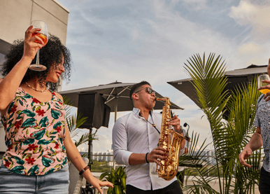 Saxophone player and woman dancing with a drink on a patio at Pinstripes