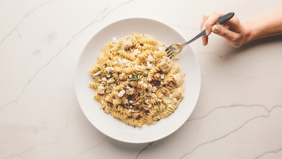 Chicken and goat cheese pasta from Pinstripes with a fork grabbing a bite of pasta.
