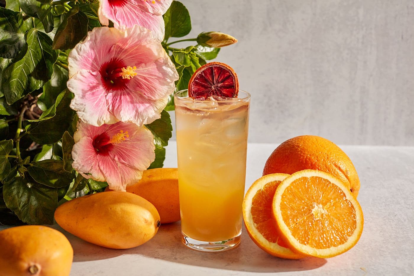 Pinstripes Puccini cocktail with New Amsterdam Vodka, mango juice, peach syrup, citrus sour mix, and sparkling wine served over ice, garnished with blood orange.
