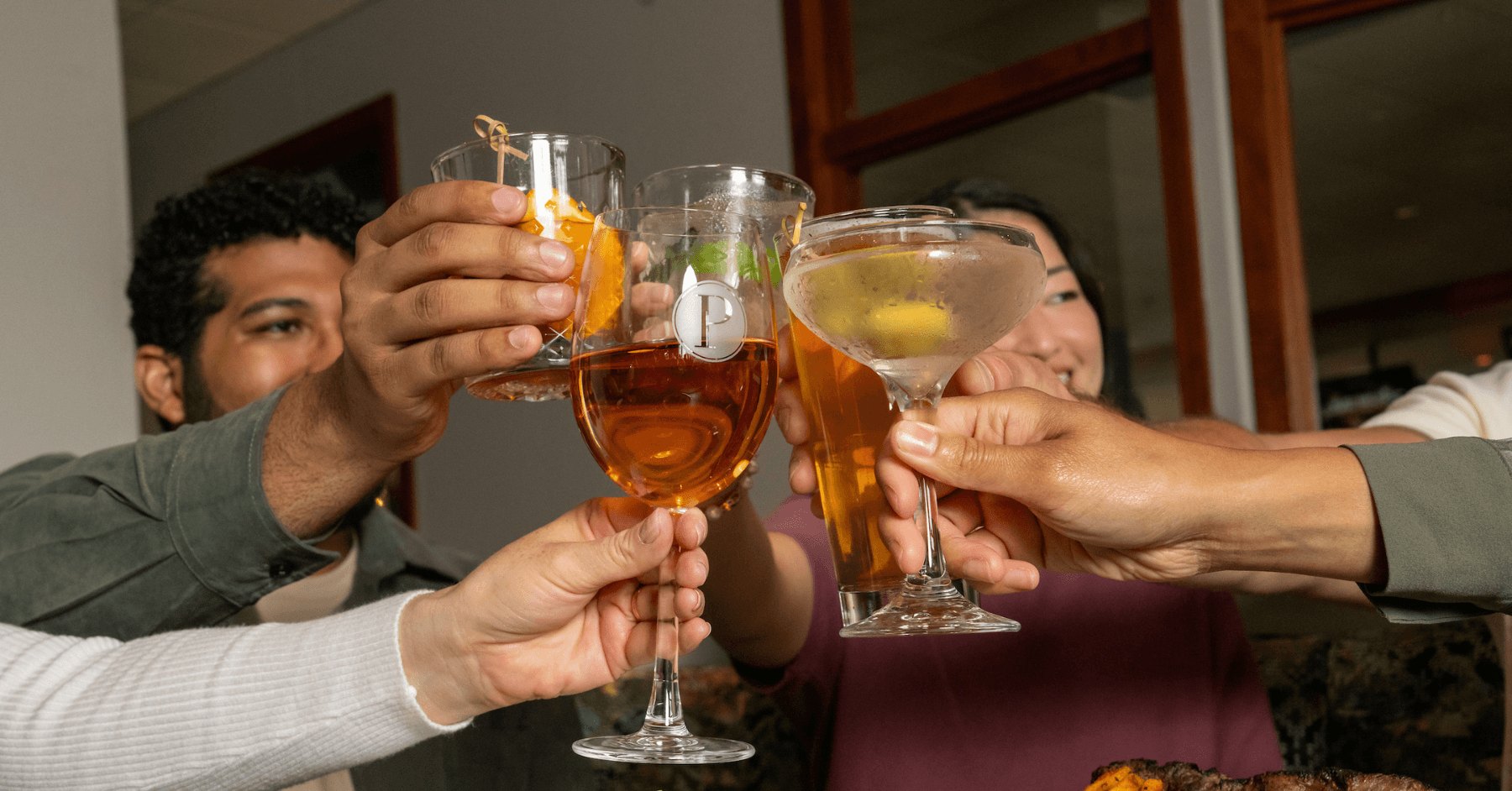 Five friends raising an assortment of beers and cocktails together at Pinstripes.